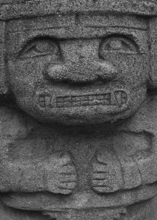 A statue made of stone and with a big round head.