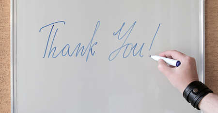 Hand writing the words THANK YOU on white blackboard.の写真素材