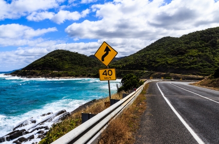 The yellow bend and 40 km h speed limit signs on the great ocean road in Victoria,Australiaの写真素材