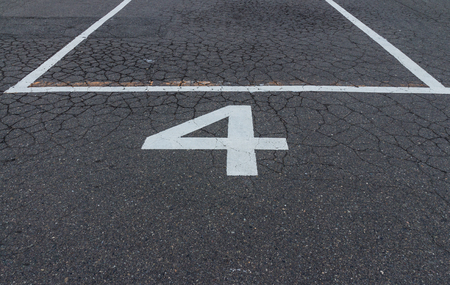 The white number four bus park sign on the tarmac street