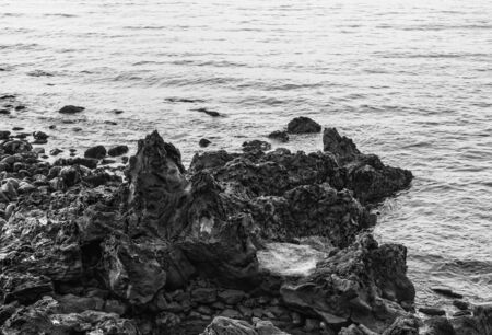 Black and white of stone beach near Dragon Head Rock or Yongduam Rock in Jeju Island, South Koreaの写真素材