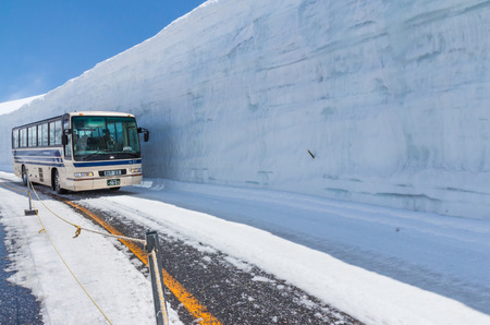 TATEYAMA, JAPAN - MAY 10, 2014: The bus move along snow corridor on Tateyama Kurobe Alpine Route, Japanese Alp in Tateyama, Japanのeditorial素材