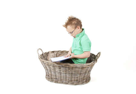 Young boy is reading a book in a basket.の写真素材