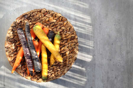 Colorful carrots, yellow, orange and purple.  Basket with vegetables on a kitchen counteの写真素材