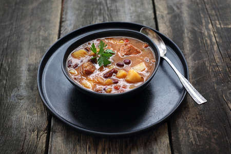 Soup in a black plate on a wooden background.の写真素材