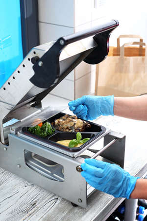 The gastronomy employee packs food into take-out boxes.