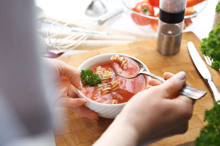 The woman is eating tomato soup. A bowl of hot, appetizing homemade tomato soup with the addition of pasta.の写真素材