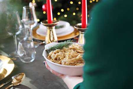 Christmas dinner, woman serves traditional Christmas dishes at the table. Traditional Christmas dishes, festive table setting. Horizontal composition.の写真素材