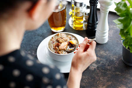 Traditional Polish sour rye soup with sausage and potatoes. The woman is eating the soup.の写真素材