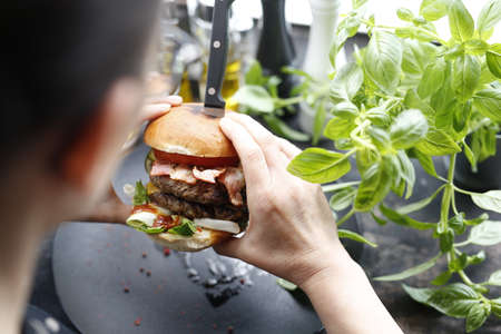 eating a hamburger. Appetizing dish served on a black plate .Culinary photography, food photography.の写真素材