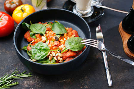 Tomatoes baked with spinach and peanuts. Food served on a plate, food styling, serving suggestions, culinary photography.の写真素材