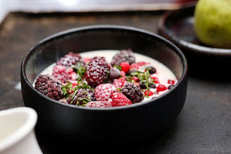 Fruit breakfast. Granola with fresh fruit. Granola with fresh fruit. The woman is pouring milk into the bowl. A bowl of milk and fresh fruit. A healthy nutritious breakfast.の写真素材