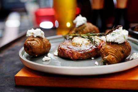 Beef steak with garlic butter, baked potatoes with cottage cheese. Food served on a plate, food styling, serving suggestions, culinary photography.の写真素材