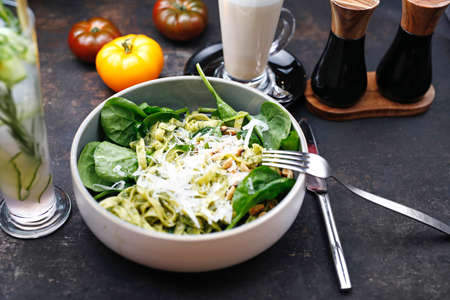 Pasta with green pesto with spinach, pine nuts and parmesan cheese. Food served on a plate, food styling, serving suggestions, culinary photographyの写真素材
