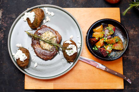 Beef steak with garlic butter, baked potatoes with cottage cheese. Food served on a plate, food styling, serving suggestions, culinary photography.の写真素材