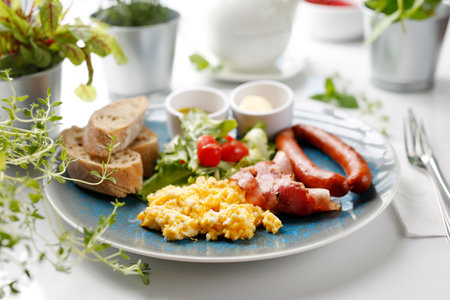 Breakfast, scrambled eggs, fried sausage and vegetable salad. Continental breakfast. Suggestion of serving a dish on a plate. food backgroundの写真素材