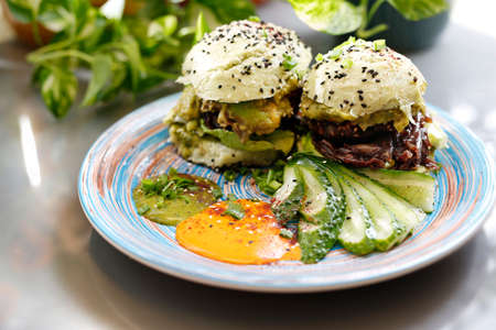 Sandwich with vegetables, fried red onion and avocado salad served with fresh cucumber and humus....