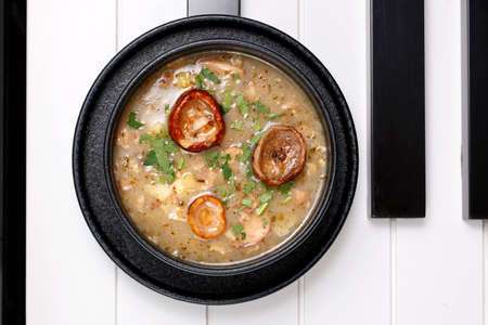 Curry soup with mushrooms and onions in a black bowl on a white backgroundの写真素材