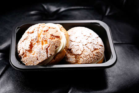Cream puff in a black box on a black leather background.