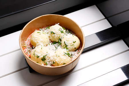Dumplings with cheese and tomato sauce in a bowlの写真素材