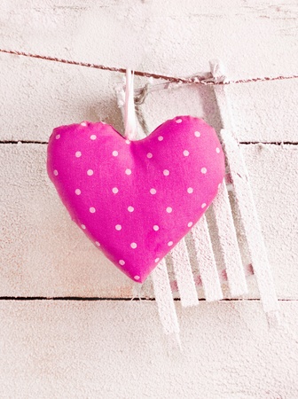 Romantic checked pink needlework heart for Valentines hanging on snow white boards with copyspaceの写真素材