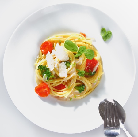 Overhead view of a prepared plate of spaghetti broccoli with parmesan ready for serving garnished with tomatoes and basilの写真素材