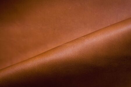 Abstract background of a section of brown leather with a single diagonal fold and copyspace