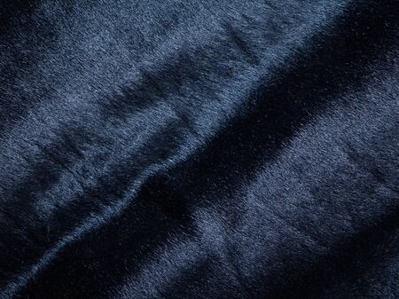 Background of a dark piece of soft supple suede leather with wrinklesの写真素材