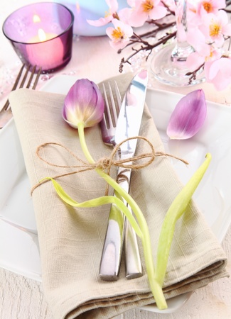 Elegant luxury table setting for a celebration with a burning candle and pink tulip and cherry blossomの写真素材