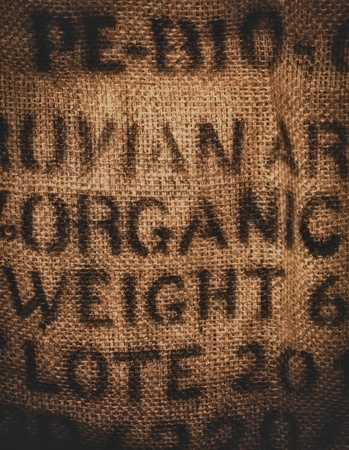 Vertical background of a twenty kilogram hessian coffee bag stamped and certified one hundred percent organicの写真素材