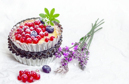 Recurrant tart still life with a freshly baked tart with whole berries balanced on a pile of fluted...