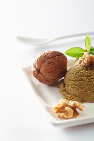 Creamy walnut icecream with halved nut kernels and a single whole walnut in its shellの写真素材