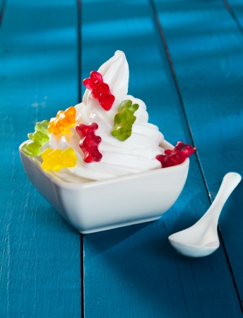Funny Frozen Yogurt with gummi bears as topping on a wooden blue backgroundの写真素材