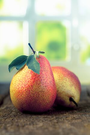 Freshly harvested ripe red and yellow pears with leaves on an old wooden table with copyspaceの写真素材