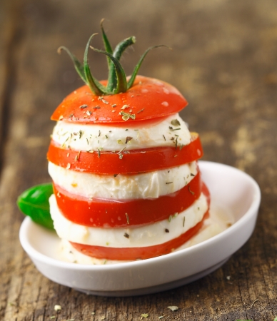 Tower of altenating slices of ripe red tomato and cheese served as a vegetarian acompaniment to a mealの写真素材