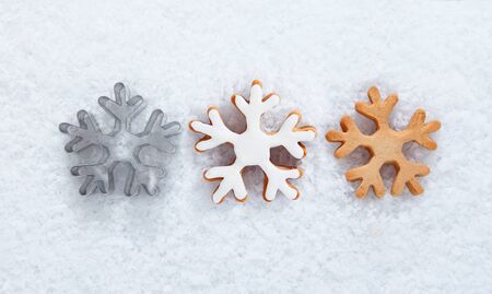 Winter background with three different snowflake biscuits in row on a bed of fresh snow for use in a...