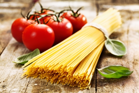 Spaghetti and tomatoes with herbs on an old and vintage wooden table