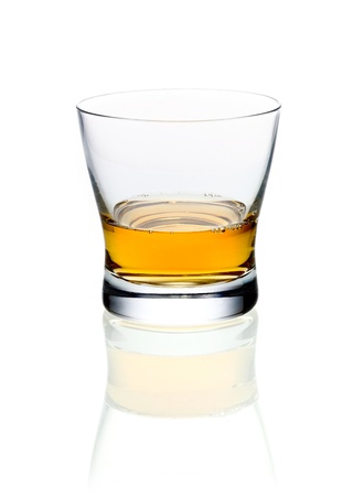 Glass of golden brandy or whisky on a white background with reflectionの写真素材