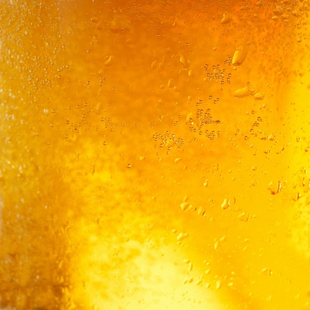 A background created from a closeup of cold light beer in a glass, with condensation droplets on the outside of the glassの写真素材