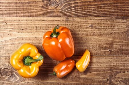 Colourful yellow and orange chili and bell peppers on textured wooden boards with woodgrain and copyspaceの写真素材