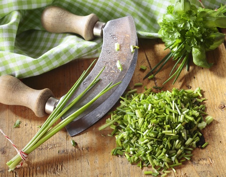 High angle view of a curved kitchen rocker blade used for chopping a pile fresh chives for use as an ingredient in cooking and saladsの写真素材