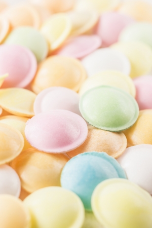 Close-up vertical background texture made of many round candies in colorful pink, orange, yellow and green tonesの写真素材