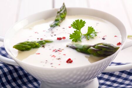 Closeup of fresh green asparagus tips in a bowl of cream of asparagus soup garnished with corianderの写真素材