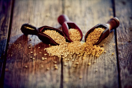 Variety of cereal grains spilling out of wooden scoops onto an old wood countertop including bulgur and couscousの写真素材