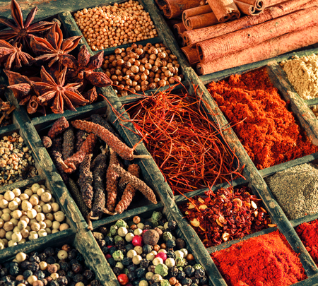Variety of spices in an old printers tray with mixed peppercorns, red cayenne pepper, saffron, star anise, and cinnamon, closeup viewの写真素材