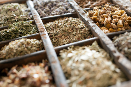 Assorted dried herbs in a printers tray with focus to chamomile flowers and a blend of mixed herbs for use in the kitchen to season and flavour foodの写真素材