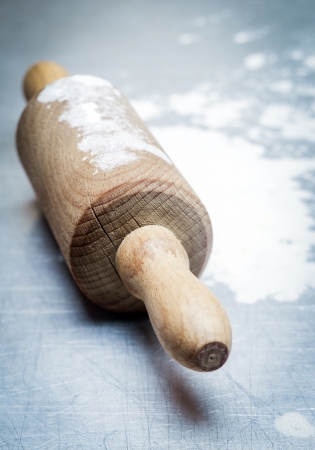 Old wooden rolling pin with scattered flour on a blue kitchen surface during baking of homemade pastries or pizzaの写真素材