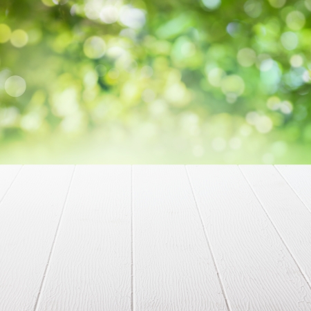 Empty table in a sun drenched summer garden for product placement with focus to the table top in the foreground