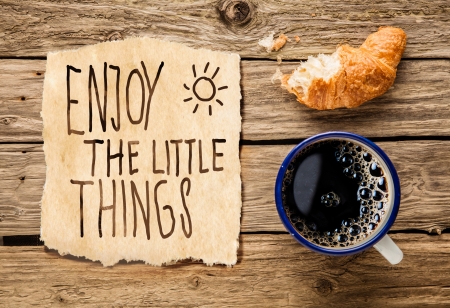 Inspirational early morning breakfast of a half eaten fresh croissant with filter coffee and a handwritten note - Enjoy the little things - reminding us to appreciate even the simple moments in lifeの写真素材