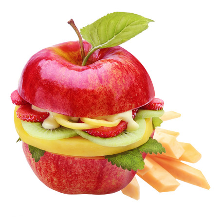 Healthy apple burger or sandwich with a farm fresh ripe red apple halved and filled with sliced tropical fruit including strawberry and kiwifruit and served with fruit batons or chipsの写真素材